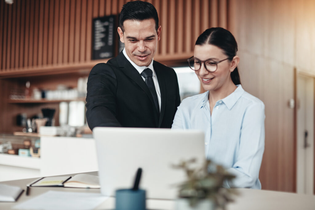 Smiling businesspeople working on a laptop together in an office Private Equity Firm