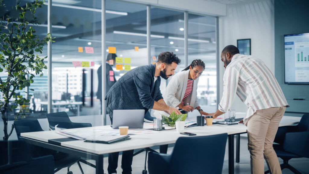Diverse Team of Professional Businesspeople Meeting in the Office Conference Room. Creative Team Around Table, Black Businesswoman, African-American Digital Entrepreneur and Hispanic CEO Talking in a Start Up Company.